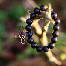  Armband svart sandelträ med 17 kulor hängandes på en gren. 