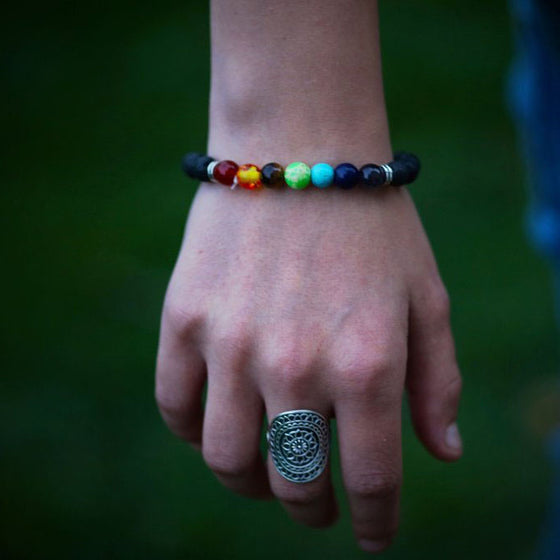 Armband Chakra med lavastenar på en armled.. De färgade stenarna har olika färger ett för varje chakra. 